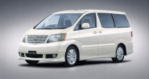 Image of a white Toyota Alphard V MS minivan viewed at a slight angle, showing the front and side profile, with integrated headlamps and a multi-bar front grille.